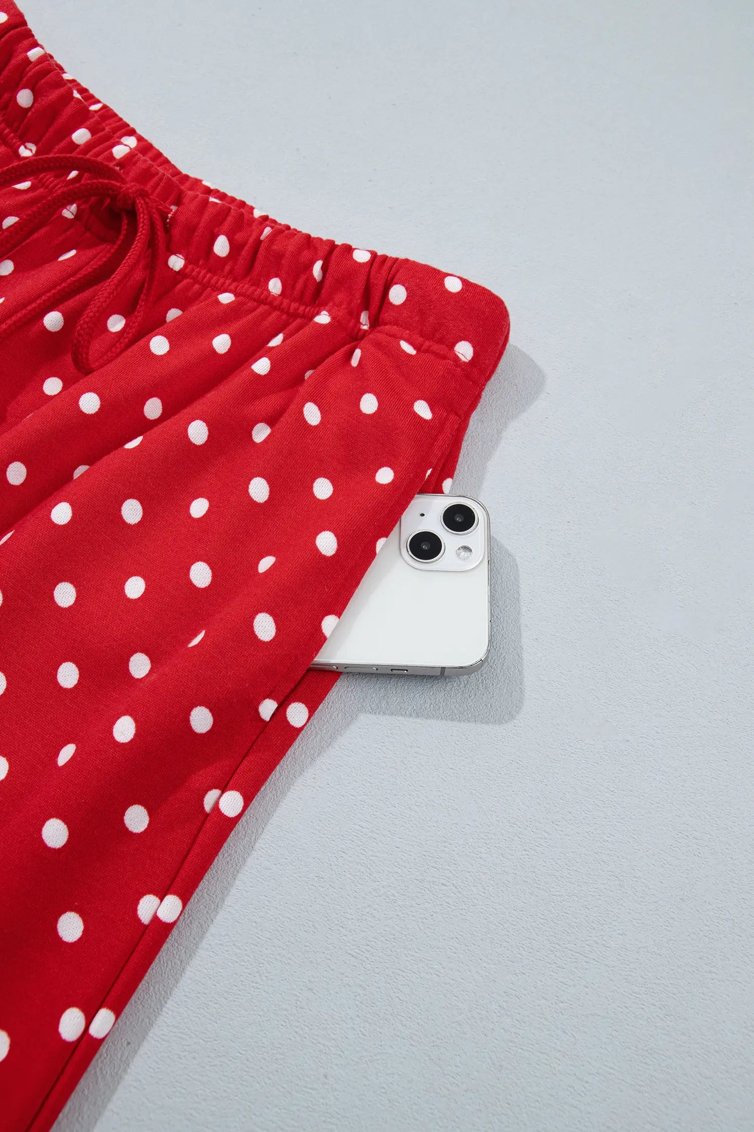 Red polka dot drawstring pants with a phone in the side pocket