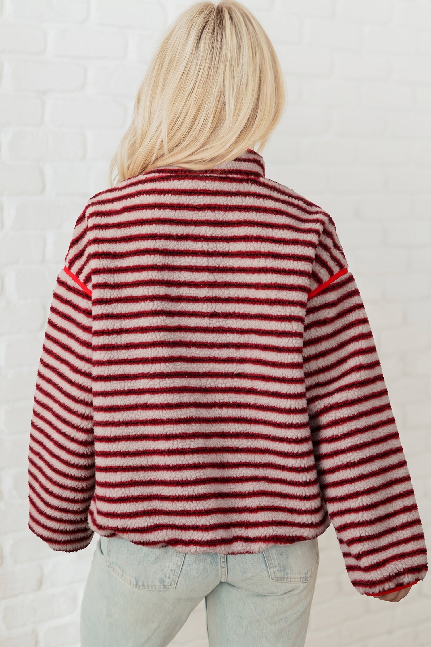 Back view of red striped sherpa pullover with red piping at shoulders and hem