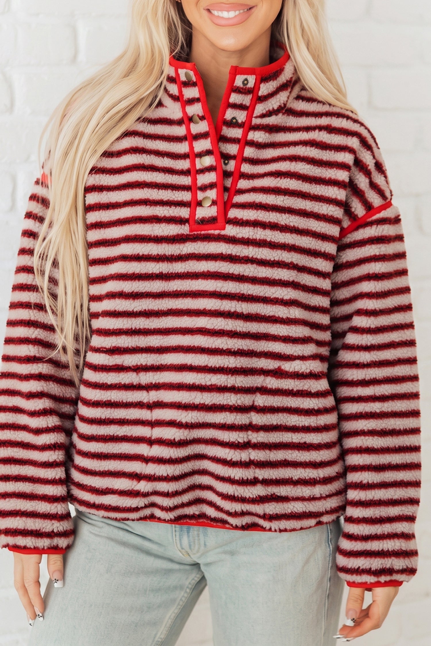 Red and cream striped sherpa snap button pullover with stand collar, worn with light jeans