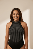 Woman wearing a black halter-neck swimsuit with bead detailing on a beige background