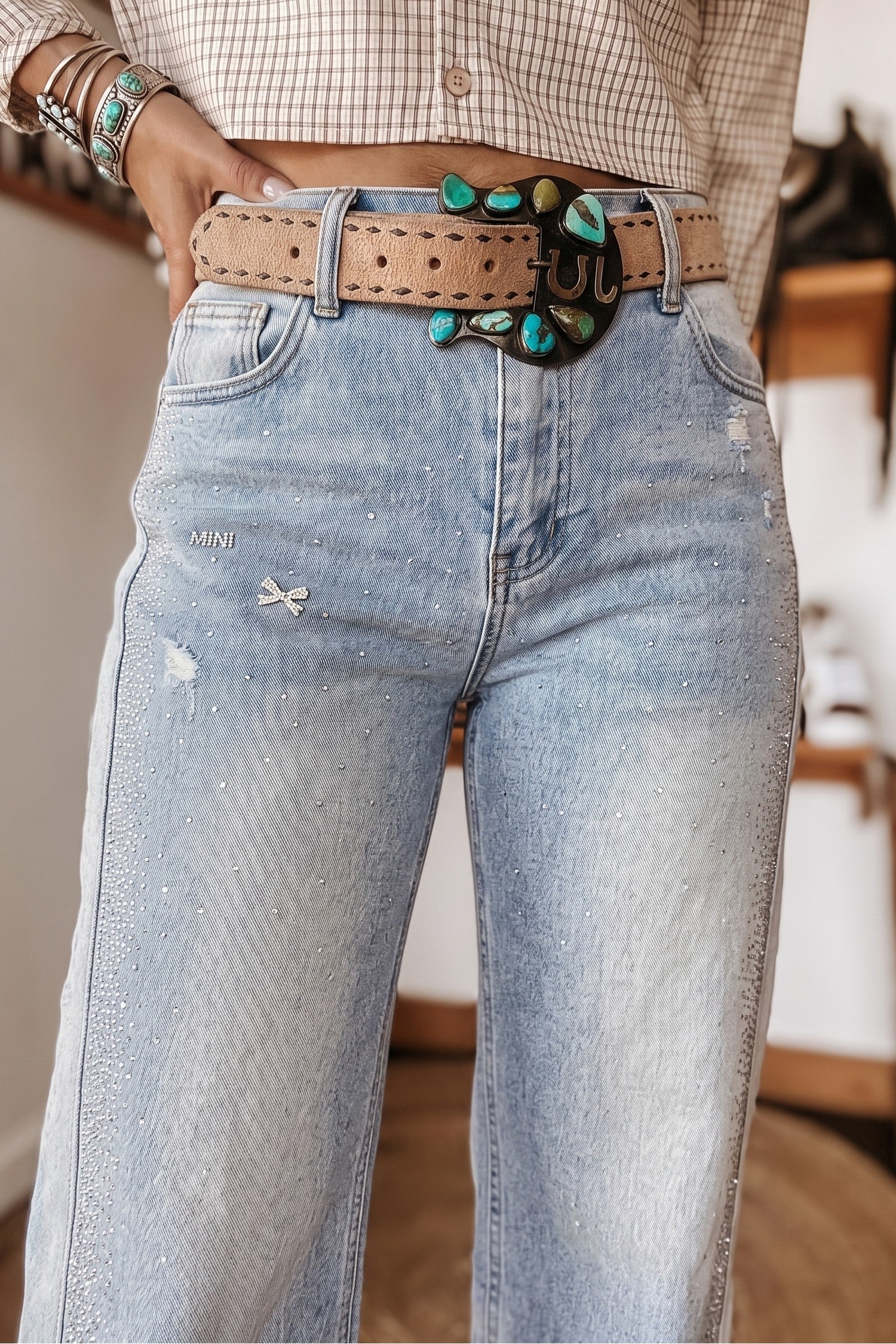 Close-up of rhinestone sparkle and bow accents on light wash western jeans