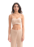 Woman wearing a beige ribbed crop top and pants on a white background