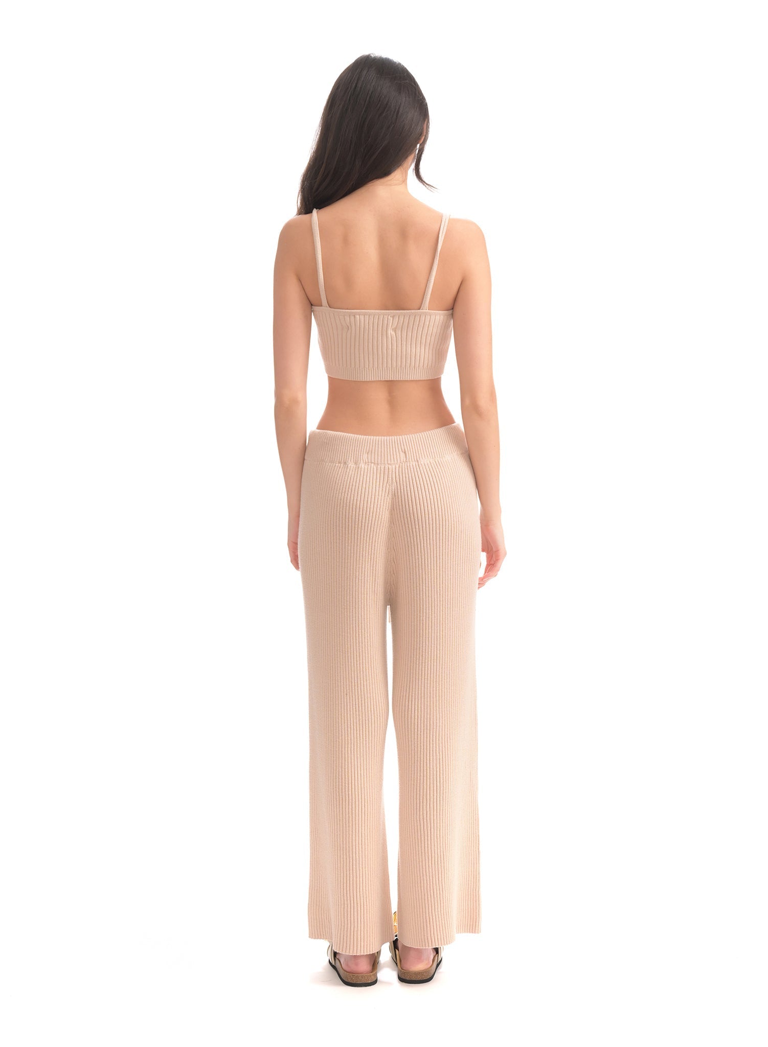Woman wearing a beige ribbed two-piece set on a white background