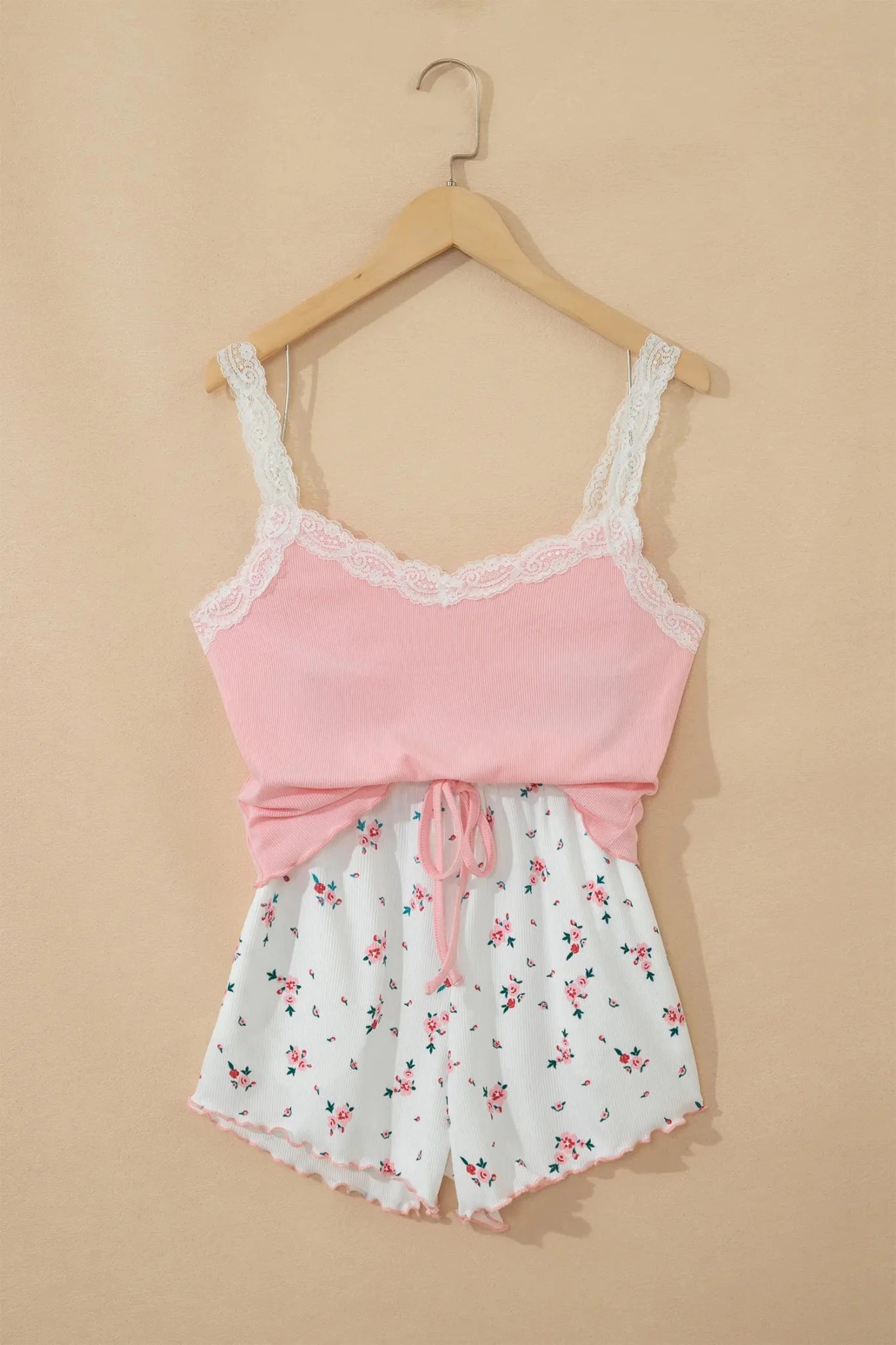 Pink lace top and white floral shorts set on a beige background
