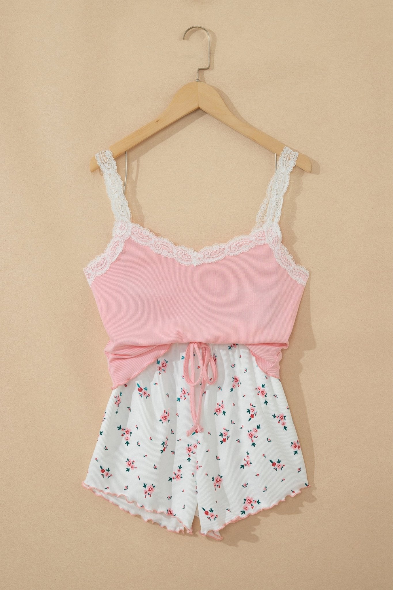 Pink lace top and white floral shorts set on a beige background