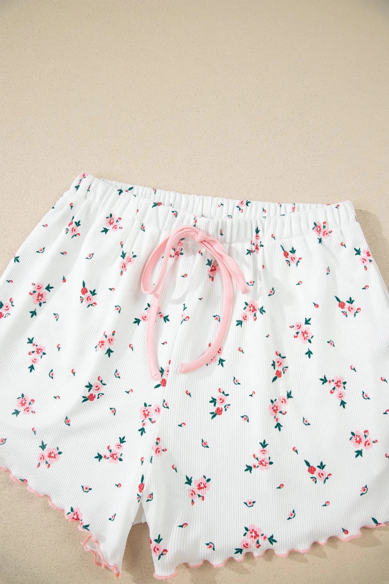 White ribbed floral shorts with pink drawstring and scalloped hem.