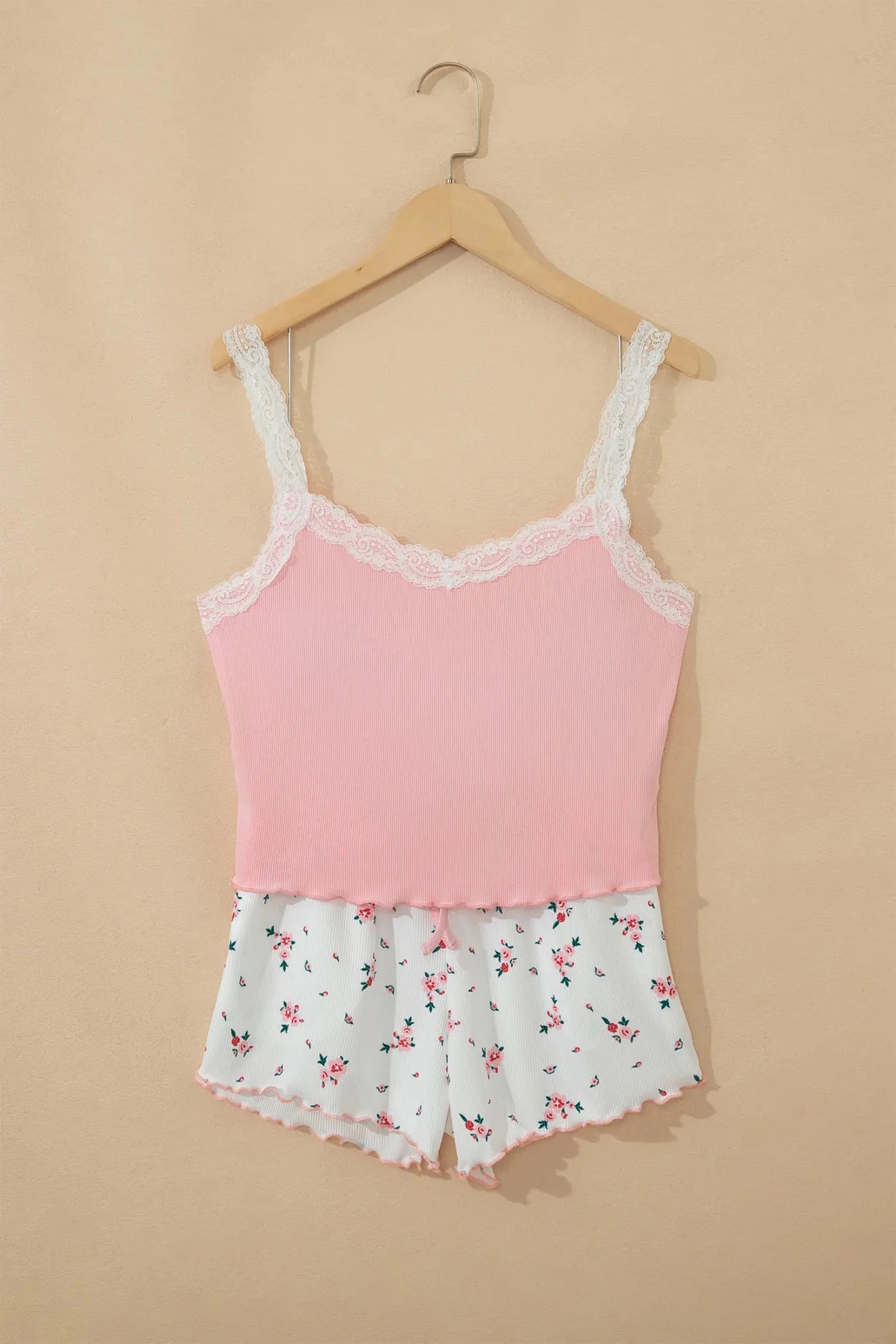 Light pink camisole with white lace trim and floral-print shorts on a hanger.