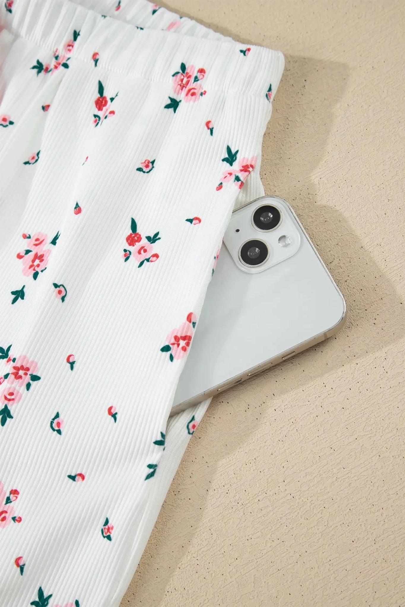 White phone with black camera lens on a floral fabric background