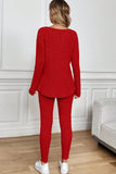 Person wearing a red knit outfit standing in a room with white walls and wooden flooring.