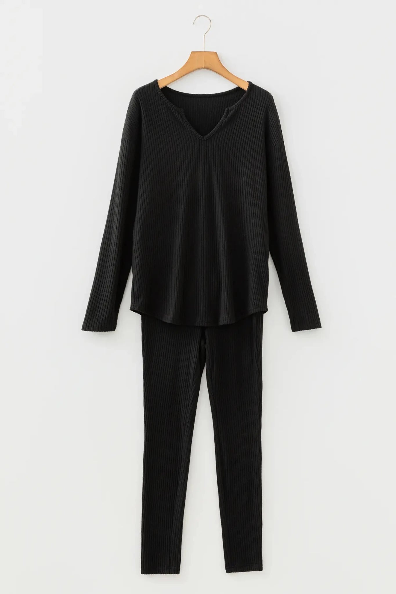 Black long-sleeve top and pants set on a hanger against a white background