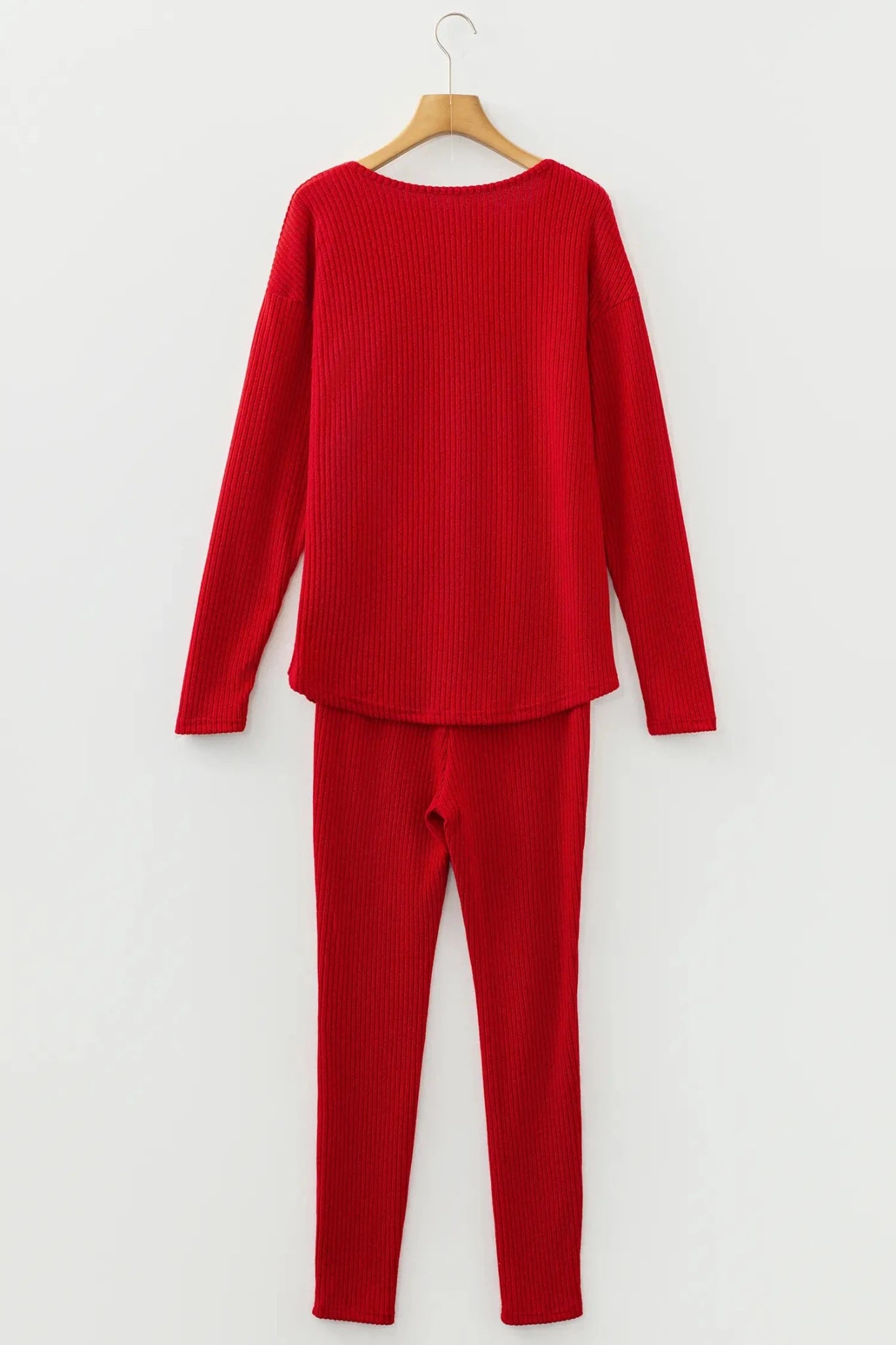 Red ribbed sweater and pants set on a hanger against a white background