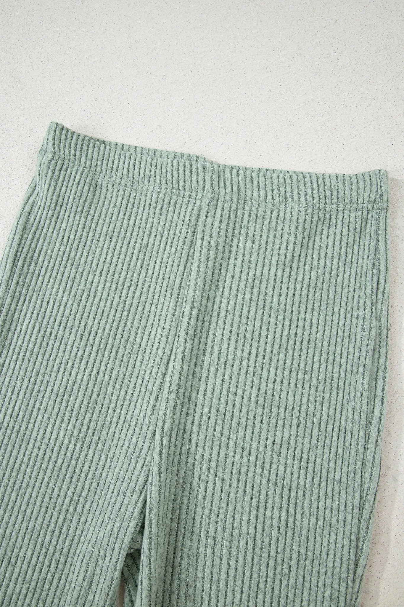 Green ribbed pants on a light gray background