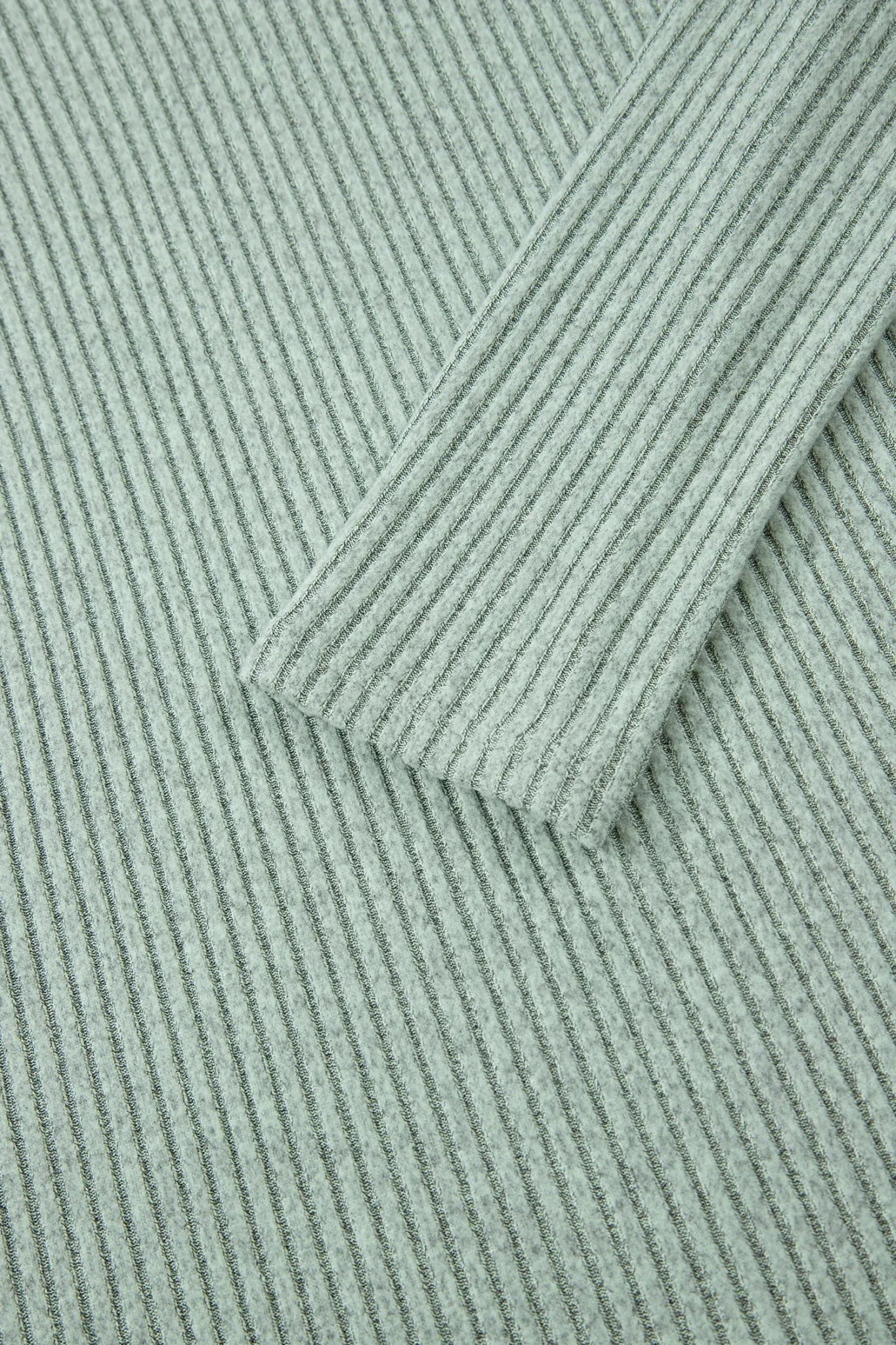 Close-up of a textured green fabric with a diagonal pattern
