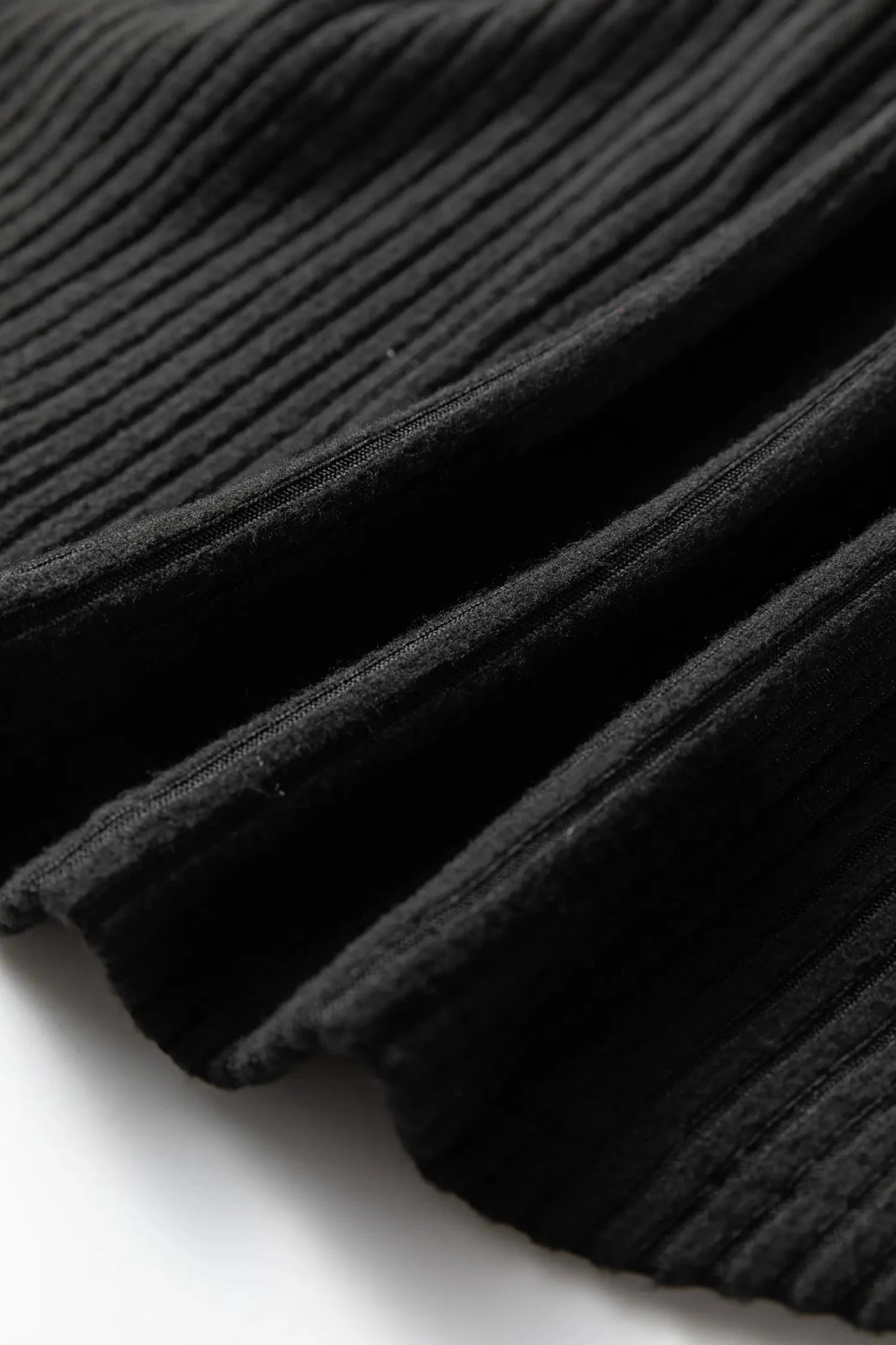 Close-up of black ribbed pleated fabric showing textured folds.