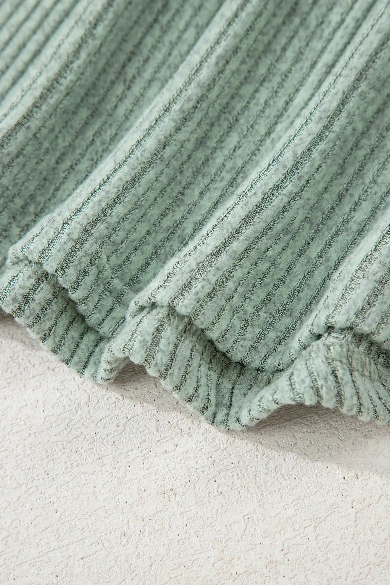 Close-up of a green textured blanket on a light background