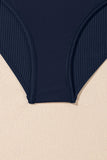 Navy blue ribbed swimsuit bottom on a beige background