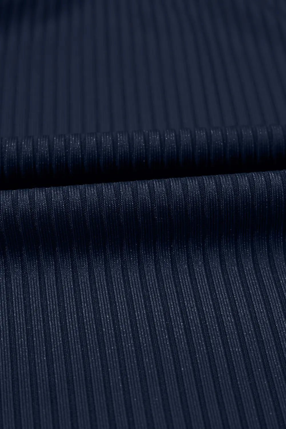 Close-up of dark navy ribbed fabric with a fine vertical stripe texture and a horizontal fold.