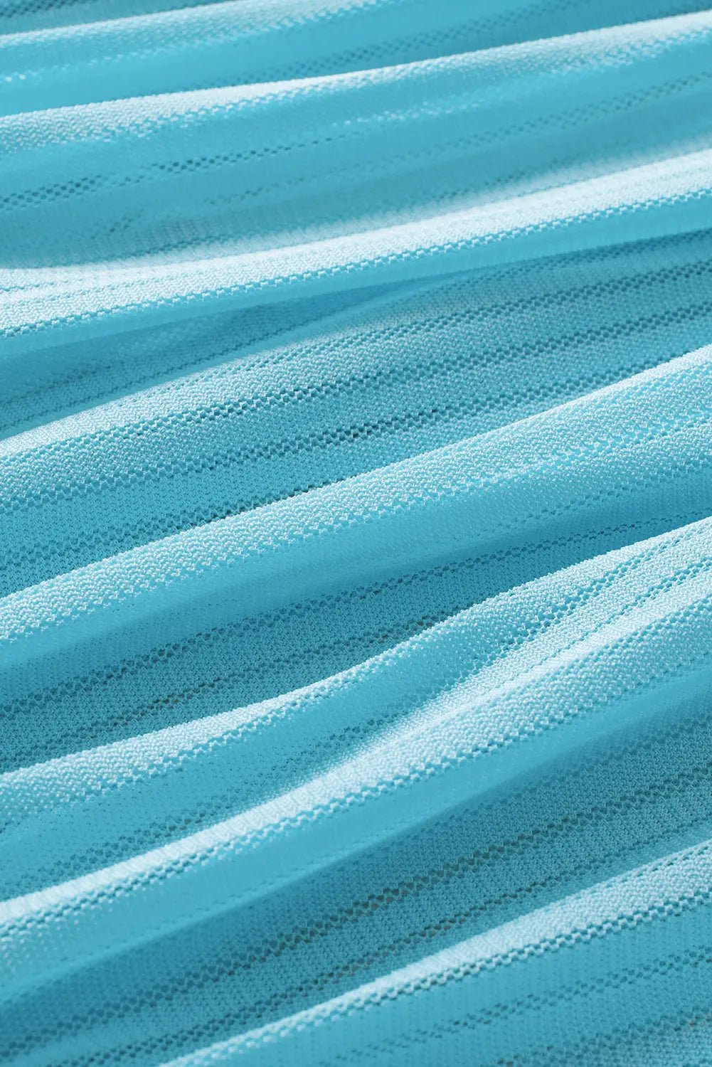 A close-up of light blue pleated mesh fabric with soft, flowing folds and a fine woven texture.