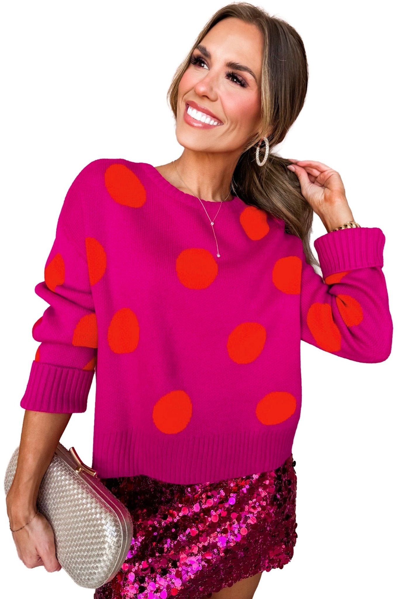 Woman in pink red-orange polka-dot sweater, magenta sequin skirt, and metallic clutch.
