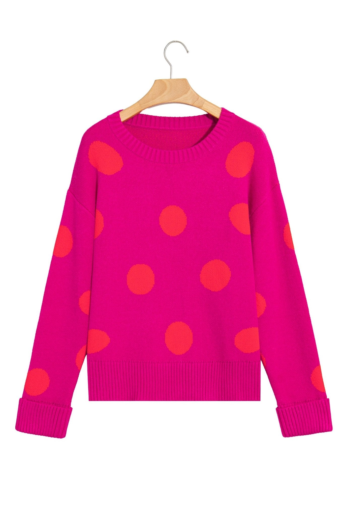 Bright pink polka-dot knit sweater on wooden hanger against plain white background.