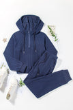 Blue hoodie and pants set on a white background with white sneakers.