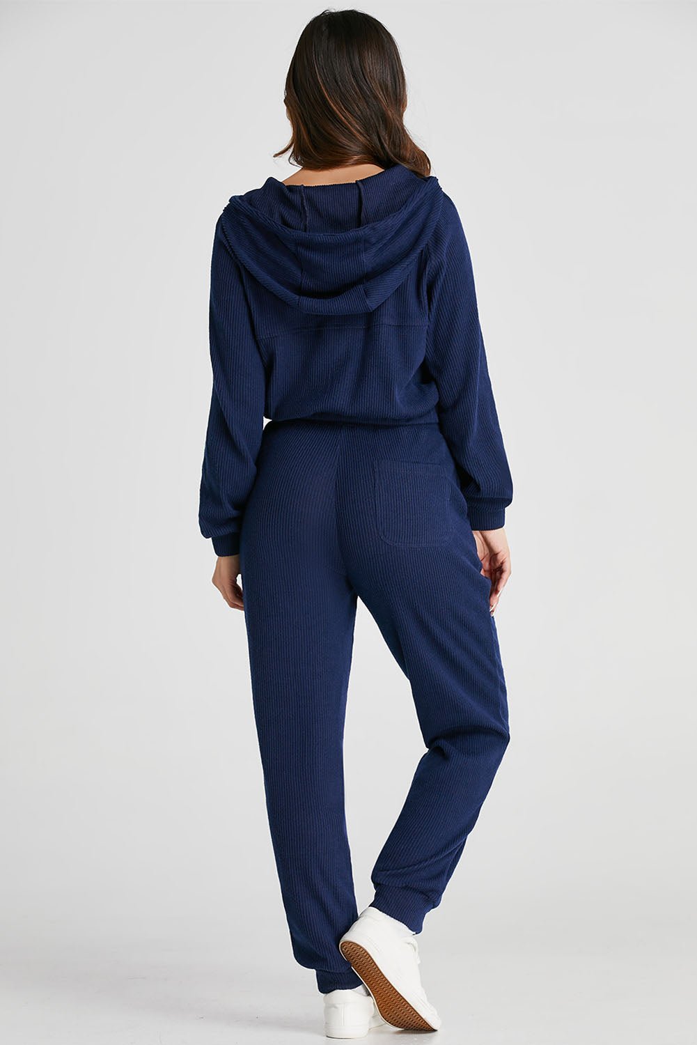 Person wearing a navy blue tracksuit on a light gray background