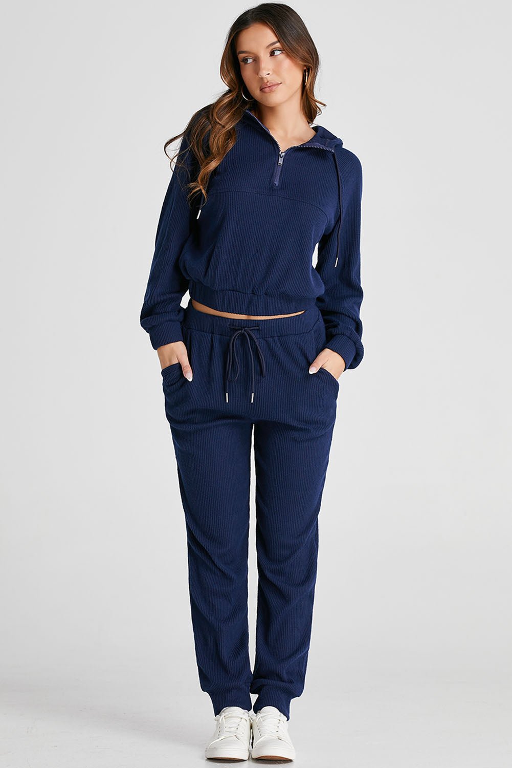 Woman wearing a navy blue tracksuit on a light gray background