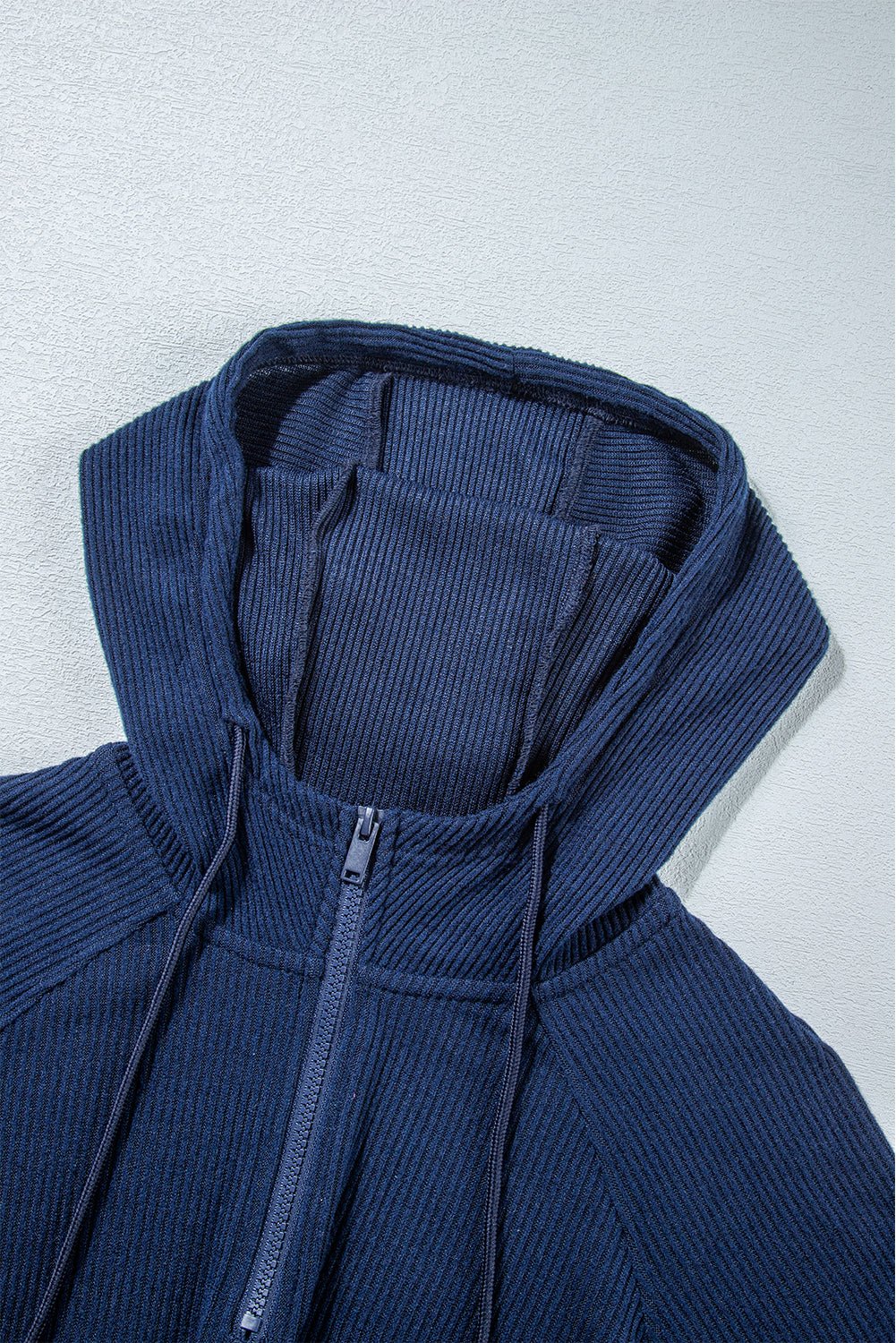 Blue ribbed hoodie with a zipper on a light gray background