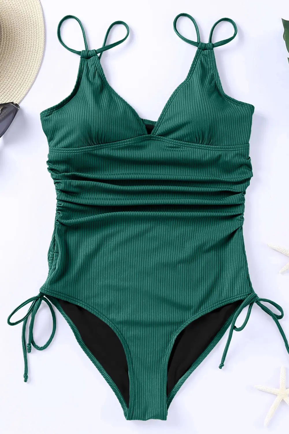 Green ribbed swimsuit with tie straps on a white surface