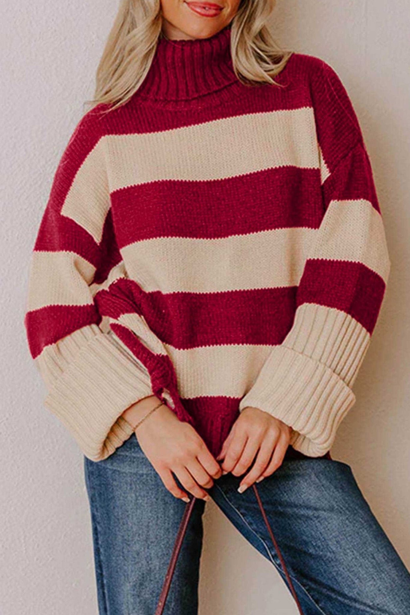Woman in chunky burgundy-cream striped turtleneck sweater with blue jeans.