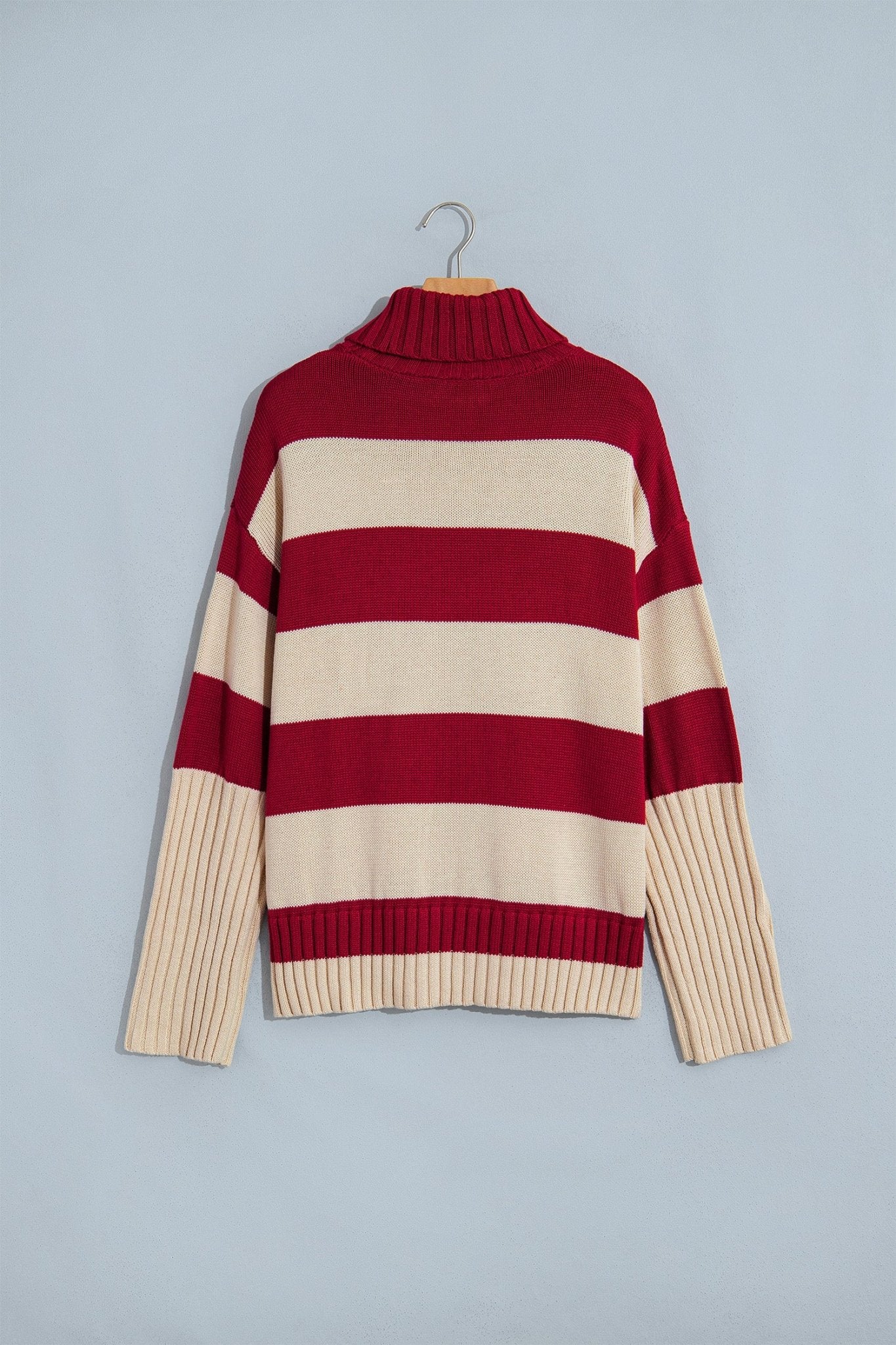 Deep red and cream striped knit turtleneck sweater on wooden hanger.
