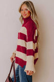 Woman in burgundy-cream striped chunky turtleneck with blue jeans and brown handbag.