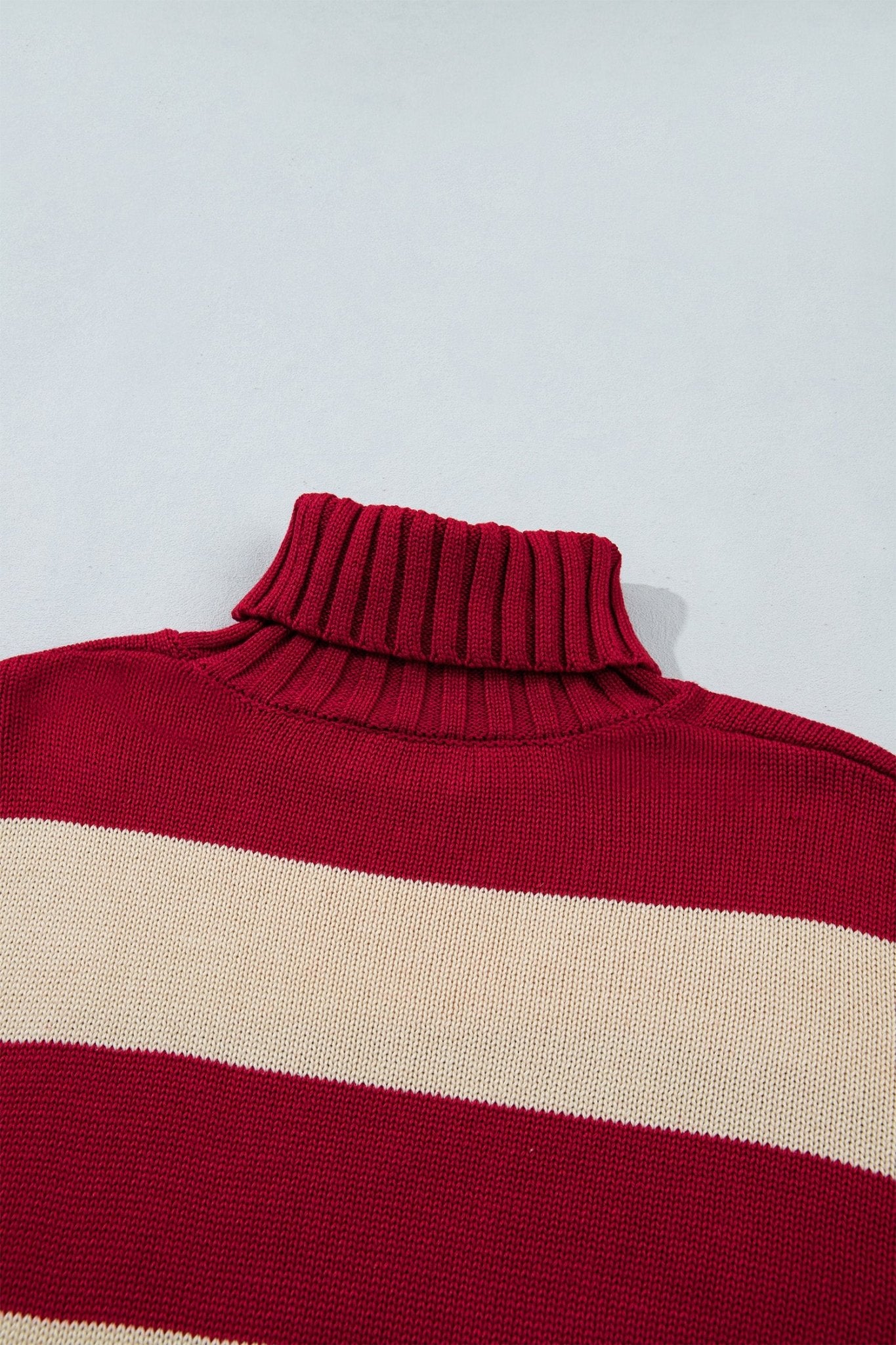 Close-up of red ribbed turtleneck sweater with horizontal cream stripes.