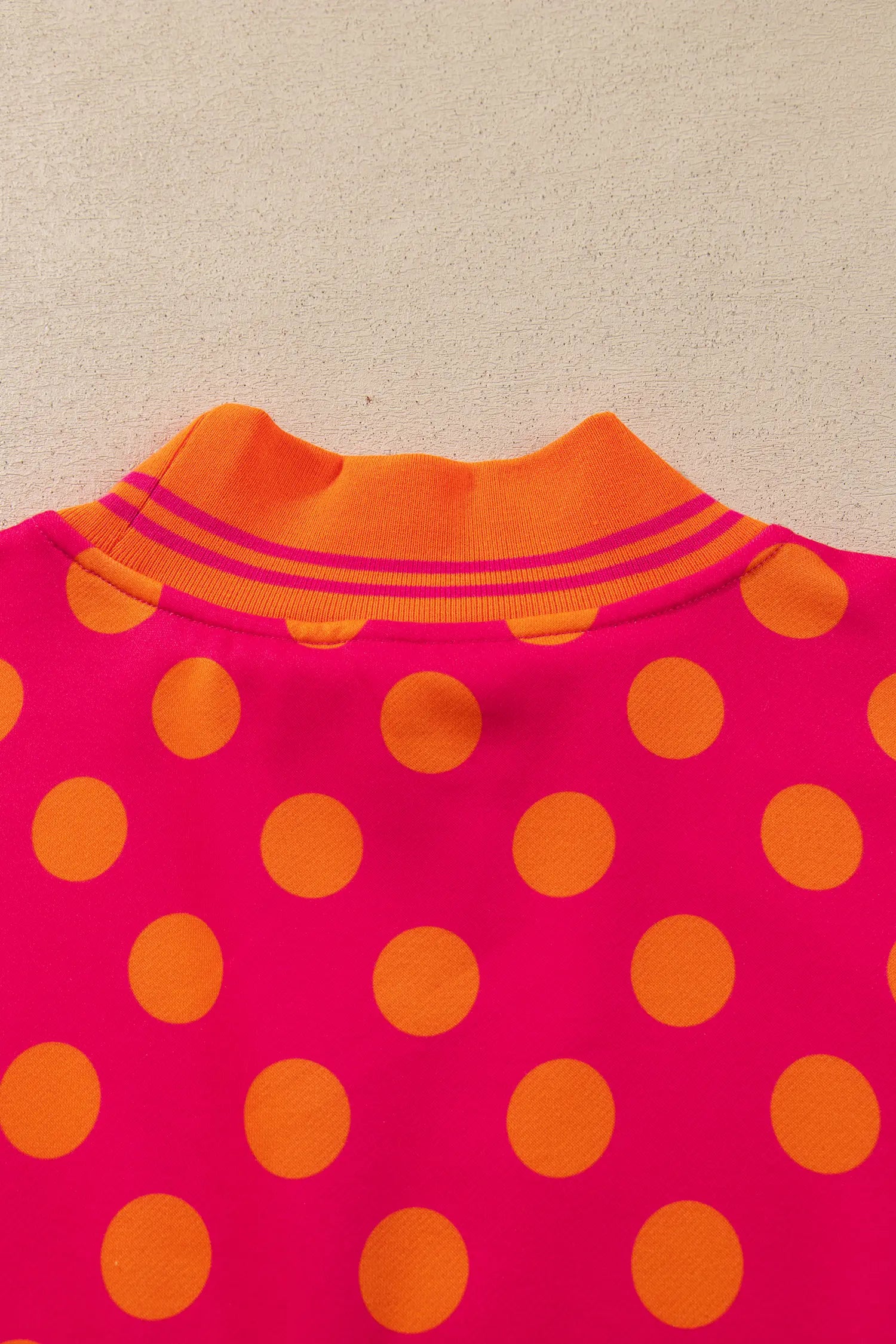 Close-up of ribbed collar on rose and orange polka dot sweatshirt