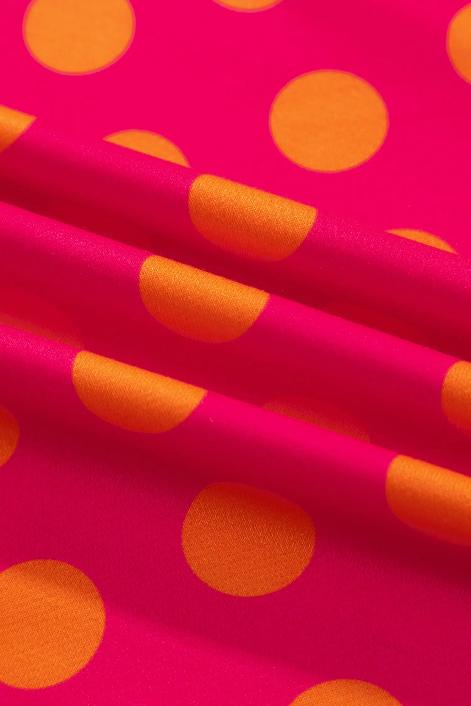 Close-up of rose fabric with large orange polka dots