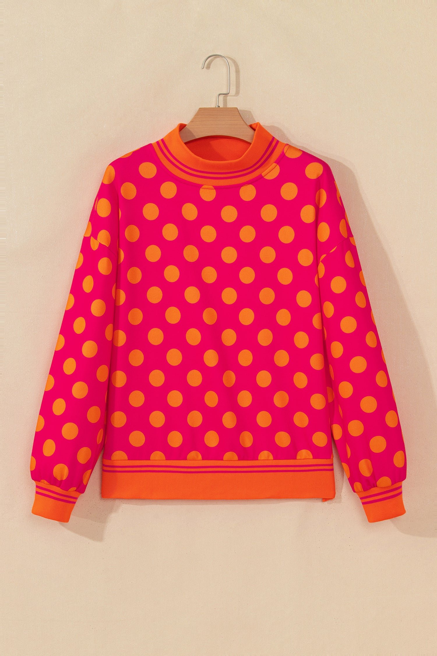 Rose sweatshirt with orange polka dots and striped mock neck on a hanger