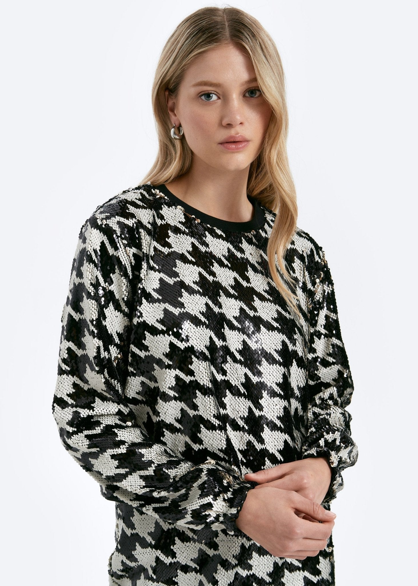 Woman wearing a black and white patterned sweater on a white background