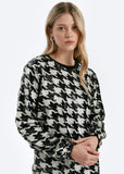 Woman wearing a black and white patterned sweater on a white background