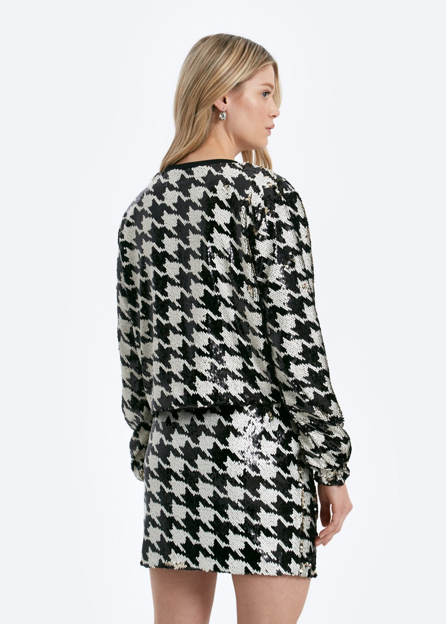 Woman wearing a black and white houndstooth pattern dress on a white background