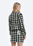 Woman wearing a black and white houndstooth pattern dress on a white background