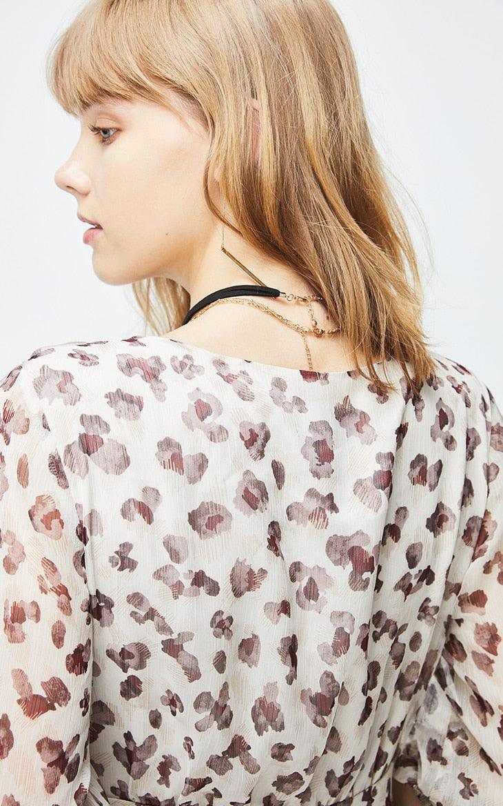 Woman wearing a floral blouse with a neutral background