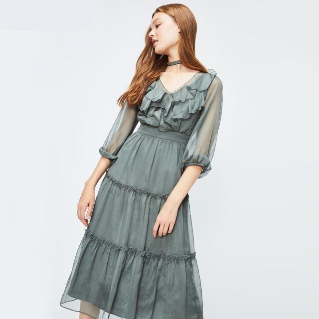 Woman wearing a green dress with ruffled details on a white background