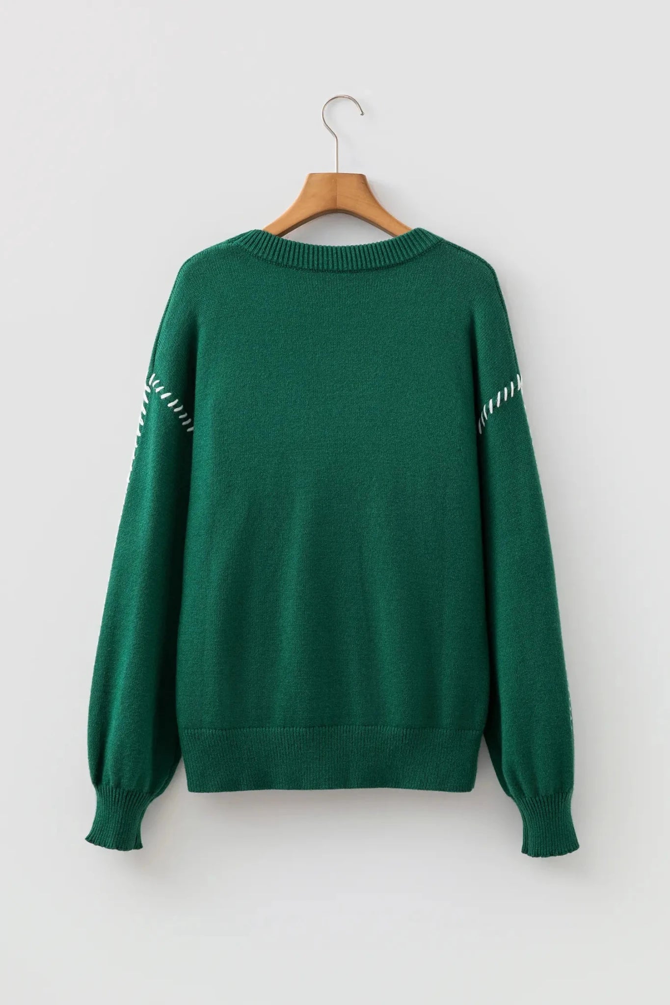 Dark green knit sweater with white geometric sleeve patterns on a wooden hanger.