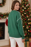 Woman wearing a green Christmas sweater with white shoulder stripes in a festive room.