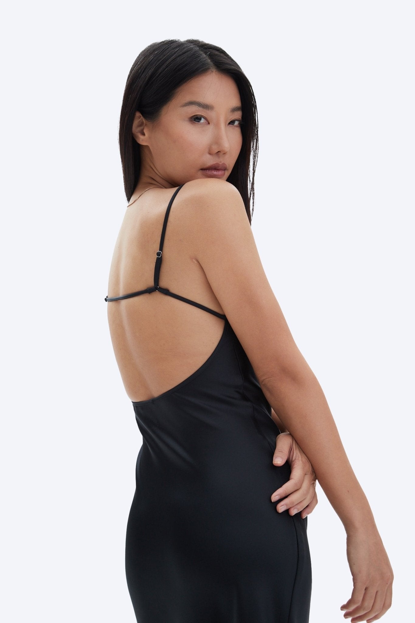 Woman wearing a black slip dress on a white background