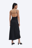 Woman wearing a black slip dress with thin straps on a white background