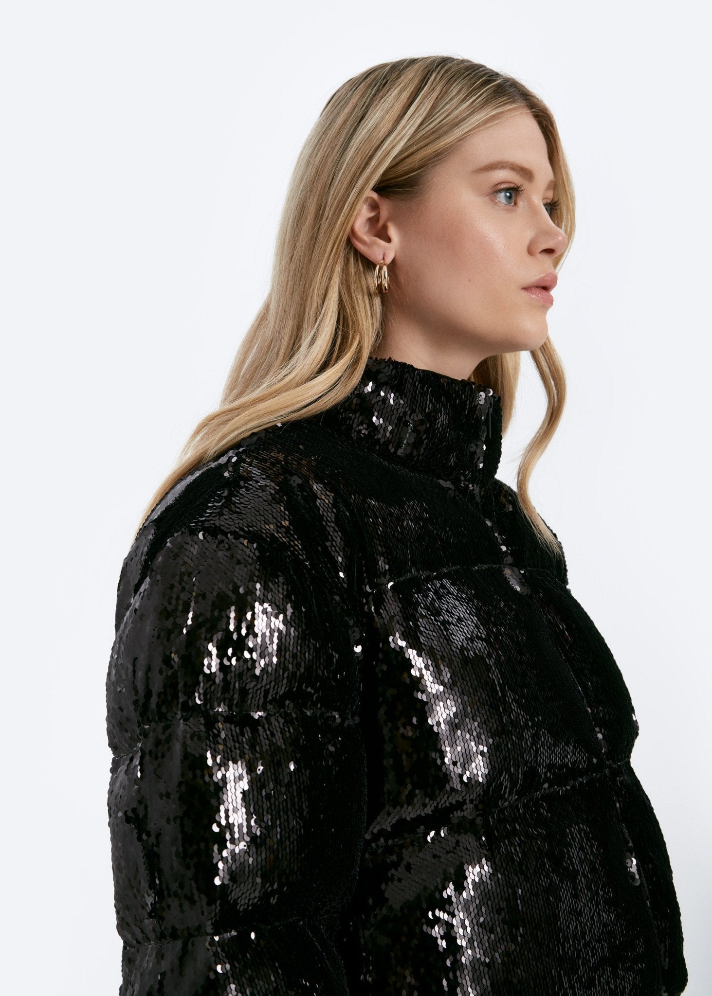 Person wearing a black sequin jacket on a white background