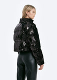 Person wearing a black sequin puffer jacket on a white background