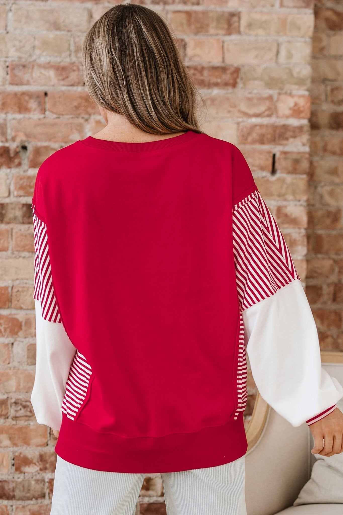Person wearing a red and white sweater with a brick wall background