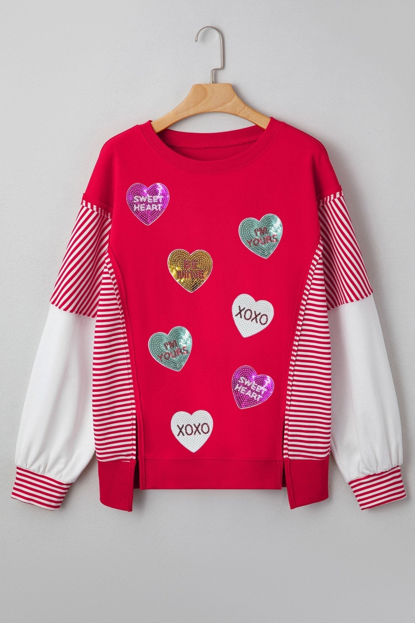 Red sweatshirt with heart-shaped stickers on a hanger against a gray background